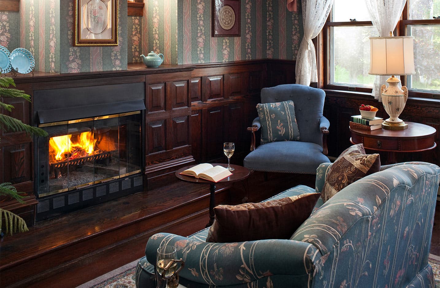 Fireplace, couch, blue chair with book and wine on table