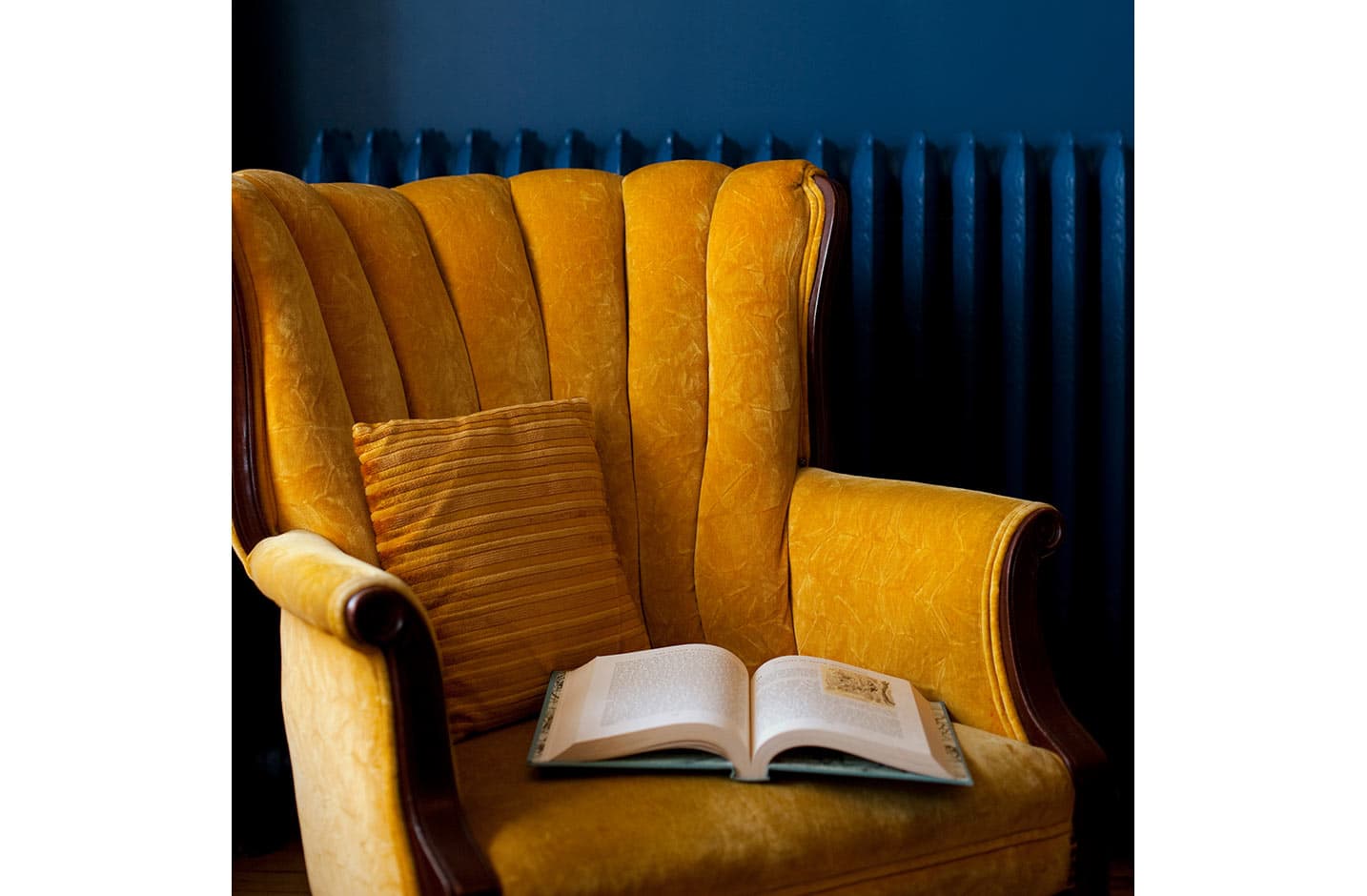 Closeup of yellow chair against blue wall, with open book