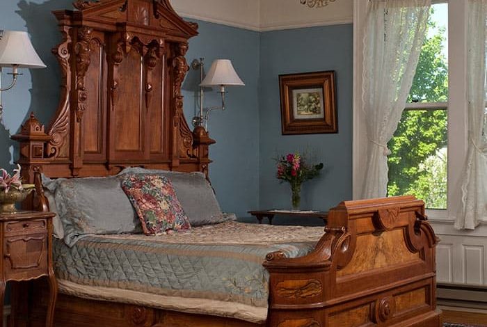 Ornate wood bed with side table, and windows