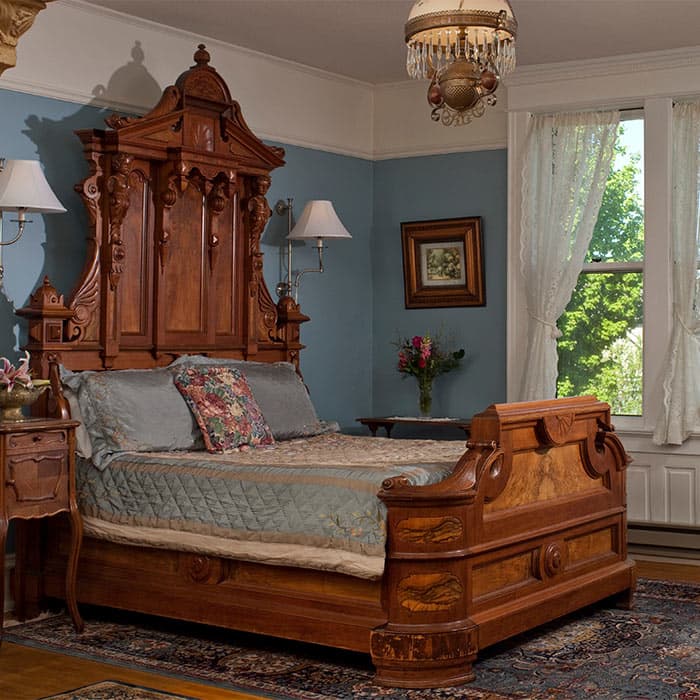 Ornate wood bed with side table, and windows