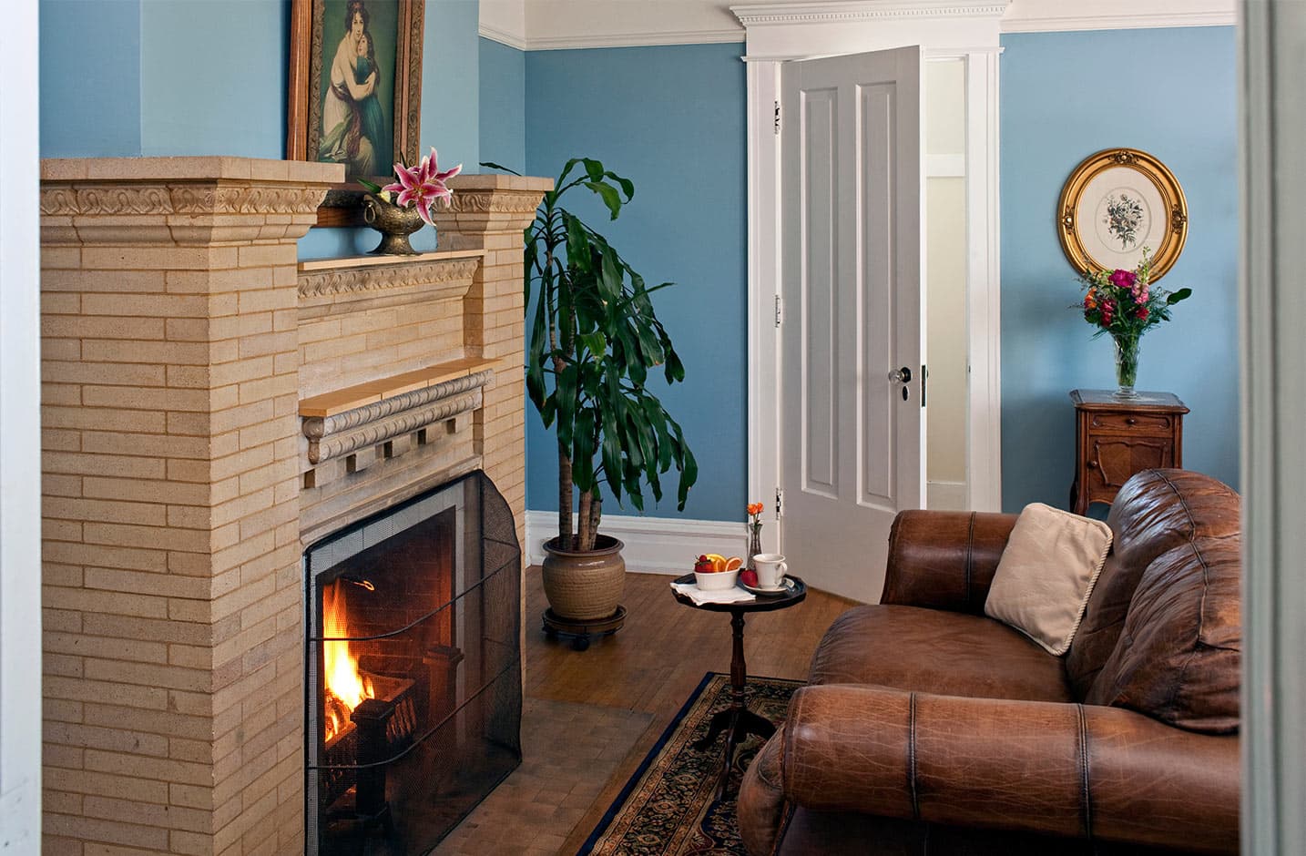 Leather couch in front of fireplace, door in background