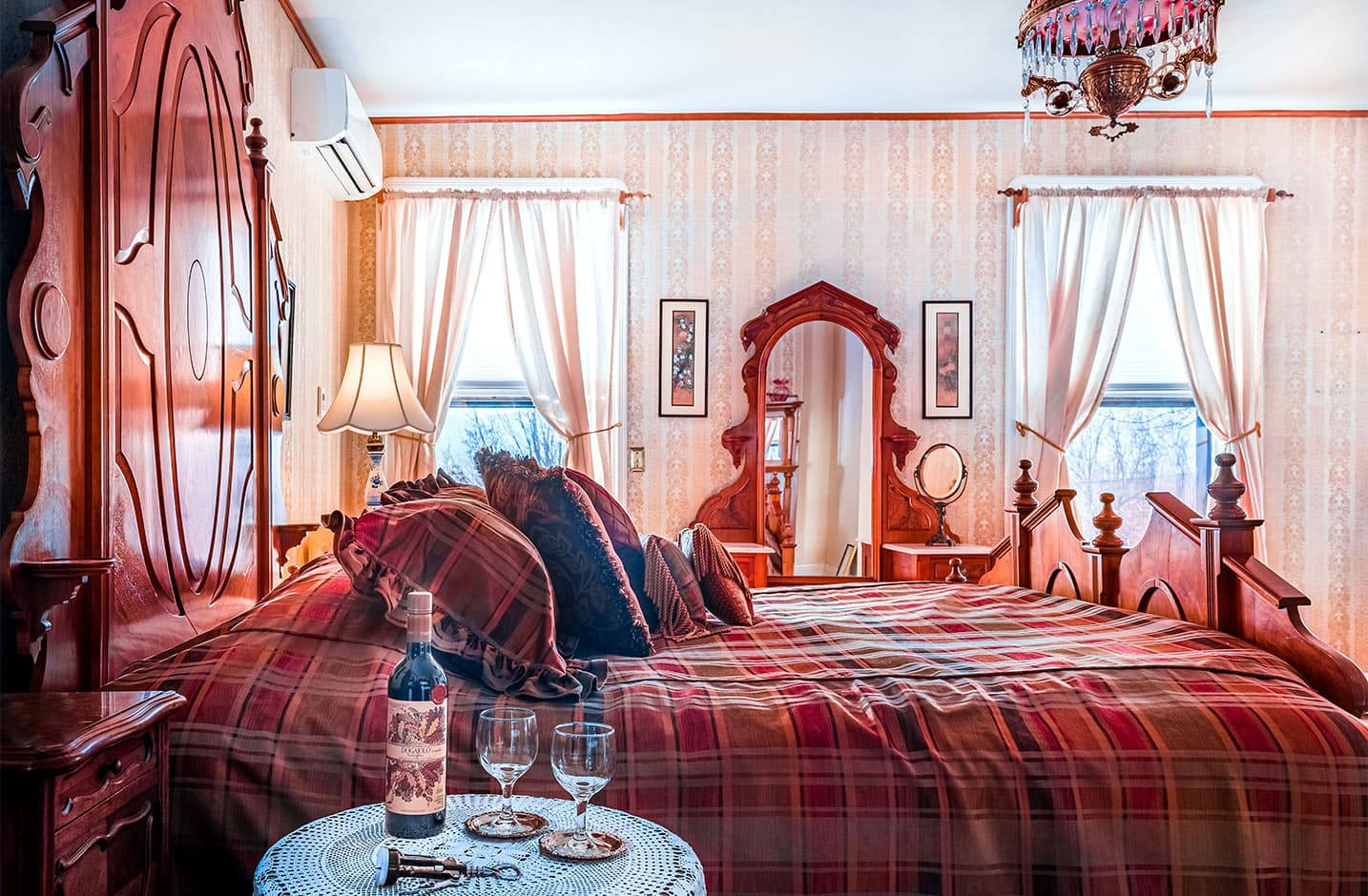 Side view of bed in Room IV with wine in foreground and dresser with mirror in background