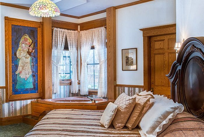 Bed in Room VIII with stain window in background