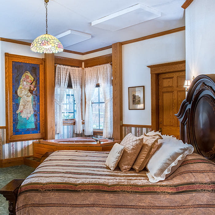 Bed in Room VIII with stain window in background