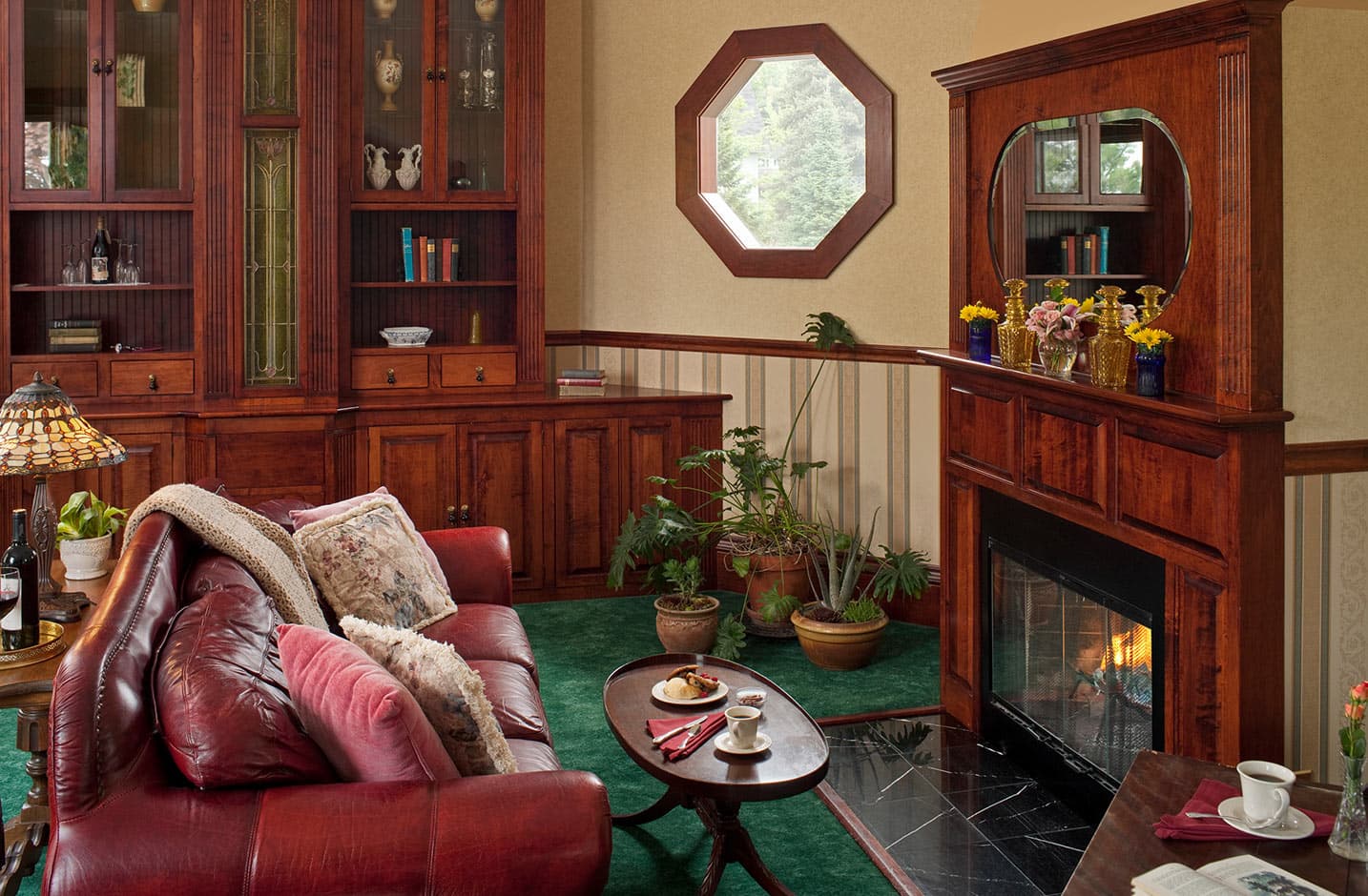 Fireplace with red leather couch and ornate wood bookshelves