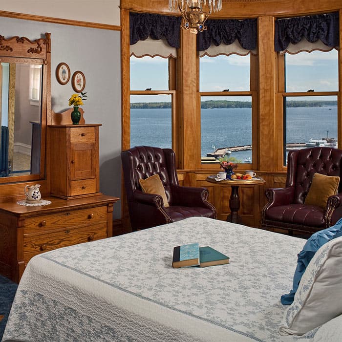 Tower Room with bed, two leather chairs and view from windows