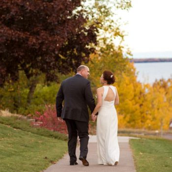 Bride and Groom walking down the sidewalk with lake in background