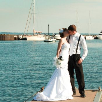 Bride and Groom Kissing on Dock with sailboats in background