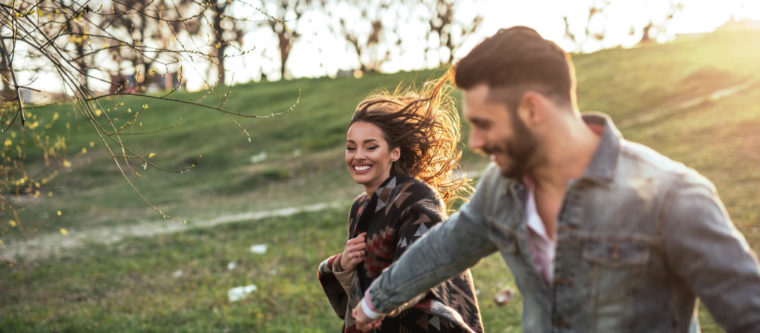 A young couple playfully gallops through an open field, one of the many fun things to do in Bayfield, Wisconsin.